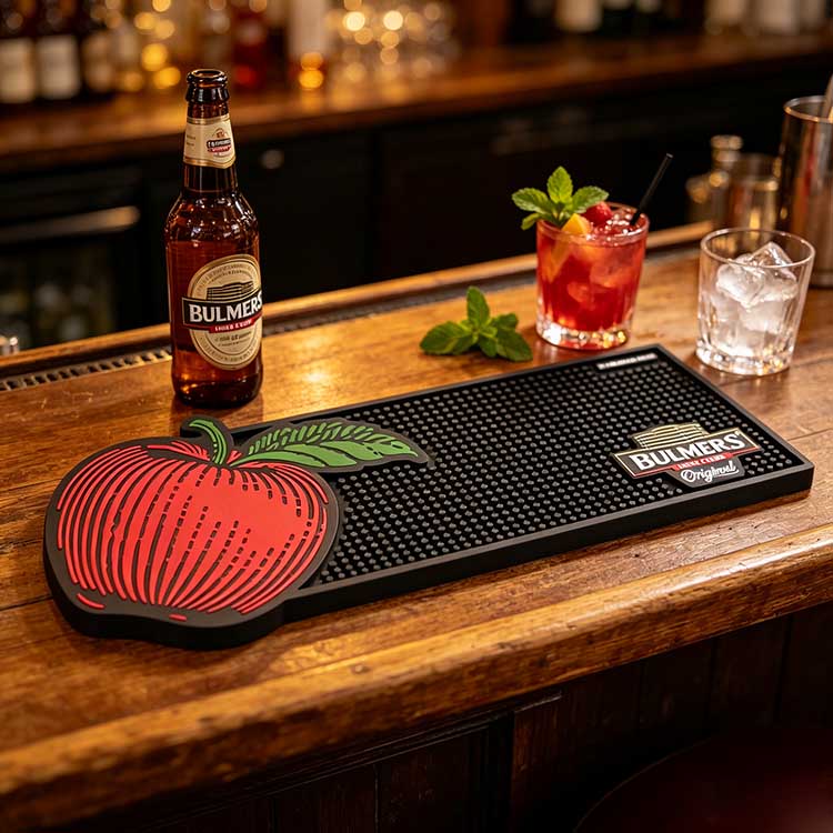Personalised Logo Bar Spill Mat Paired With Cider Bottles On Pub Counter Custom logo rubber bar mat with cider bottles on wooden pub counter personalised promotional bar spill mat
